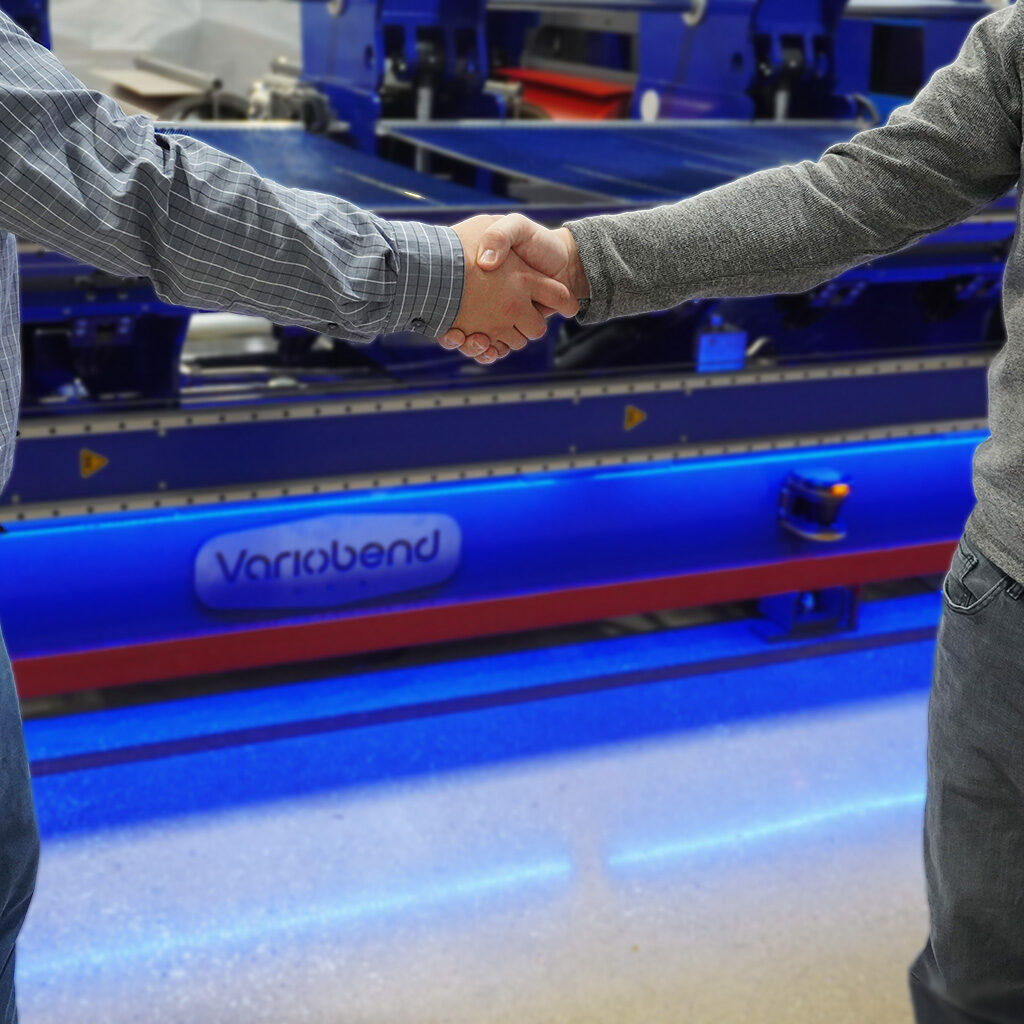 Business partners shaking hands with metal plated Variobend logo in background